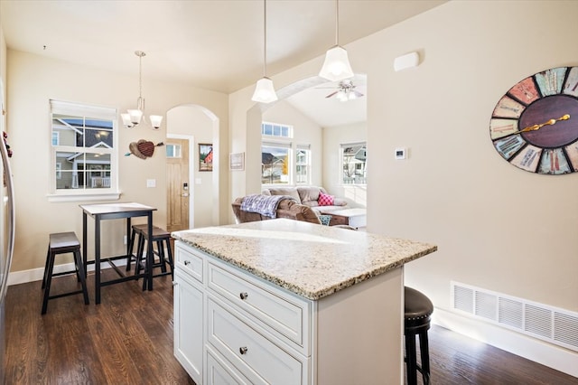 kitchen with white cabinetry, hanging light fixtures, dark hardwood / wood-style flooring, and a breakfast bar