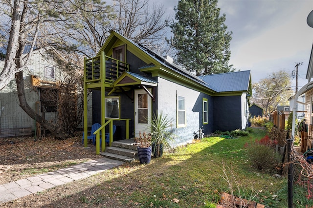 rear view of house featuring a lawn and a balcony