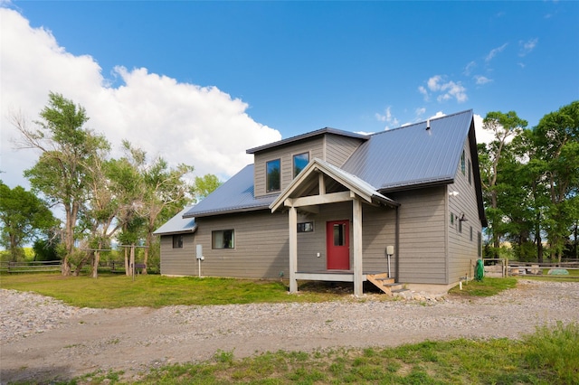 view of front of house featuring metal roof, fence, and a front lawn