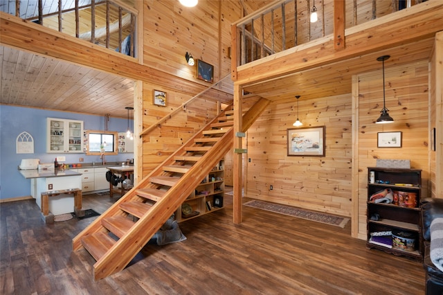 stairs with high vaulted ceiling, wood walls, sink, and hardwood / wood-style flooring