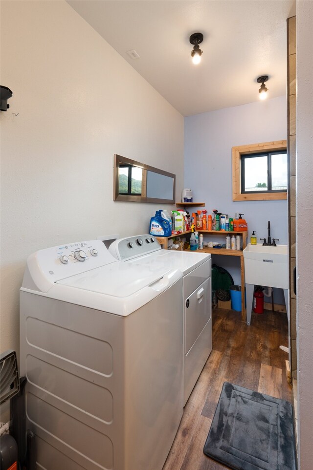 clothes washing area featuring washing machine and dryer, sink, and dark hardwood / wood-style floors