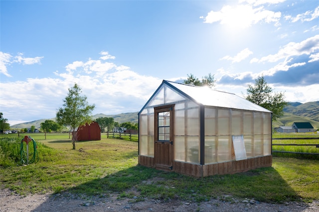 view of outbuilding featuring a yard, a rural view, and a mountain view