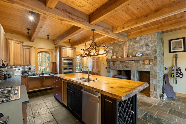 kitchen with wood counters, wood ceiling, a kitchen island with sink, sink, and beamed ceiling