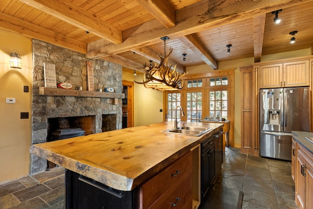 kitchen featuring stainless steel fridge, beamed ceiling, an island with sink, and wood ceiling