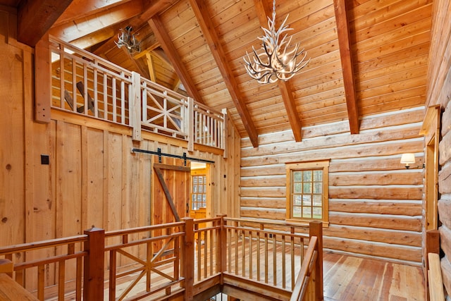 stairs featuring beam ceiling, wooden ceiling, a barn door, a chandelier, and wood-type flooring