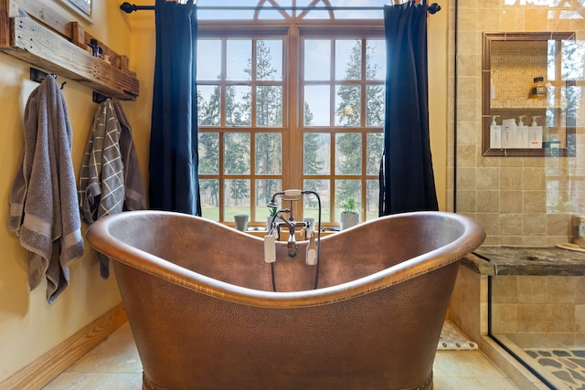 bathroom with a bath, a healthy amount of sunlight, and tile patterned flooring