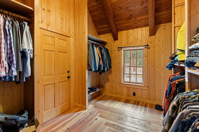 walk in closet with light wood-type flooring and lofted ceiling with beams