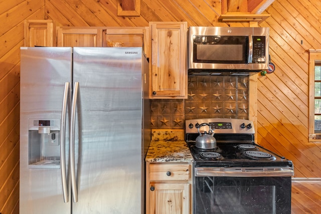 kitchen featuring wooden walls, light brown cabinetry, stone countertops, wood-type flooring, and stainless steel appliances