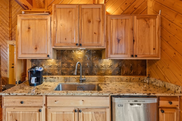 kitchen with light stone countertops, stainless steel dishwasher, wooden walls, and sink