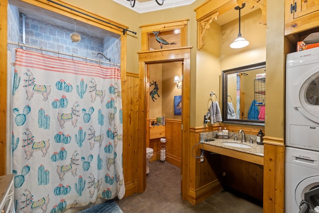 bathroom featuring walk in shower, wooden walls, sink, toilet, and stacked washer / drying machine