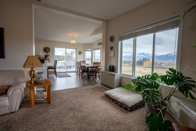 living room featuring a mountain view, wood-type flooring, heating unit, and a notable chandelier