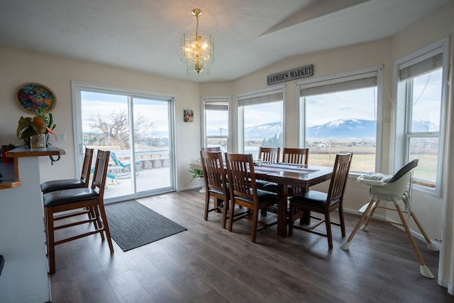 dining space with a mountain view, an inviting chandelier, dark wood-type flooring, and plenty of natural light