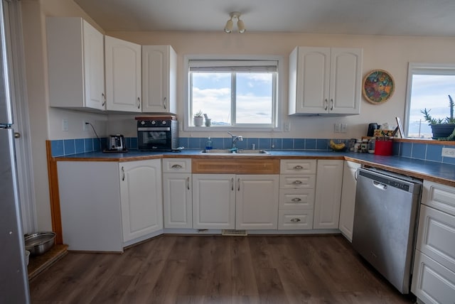 kitchen with dark hardwood / wood-style floors, white cabinets, sink, and stainless steel dishwasher