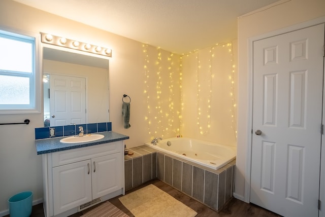 bathroom featuring tiled tub, vanity, and wood-type flooring