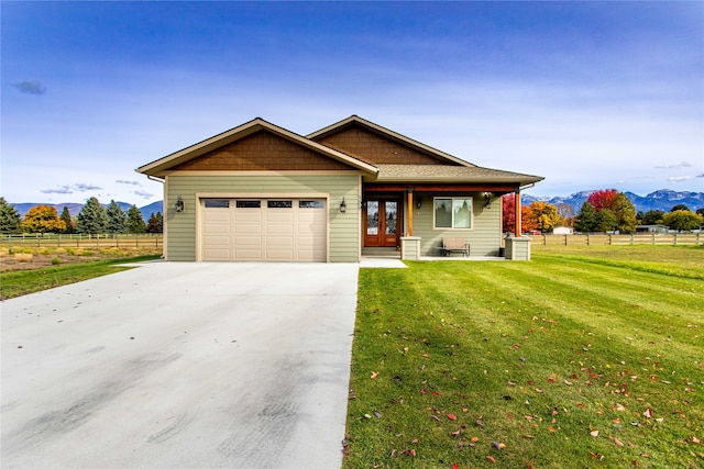 view of front of home featuring a mountain view, french doors, a front yard, and a garage