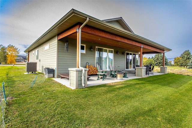 rear view of property featuring a lawn, central air condition unit, and a patio