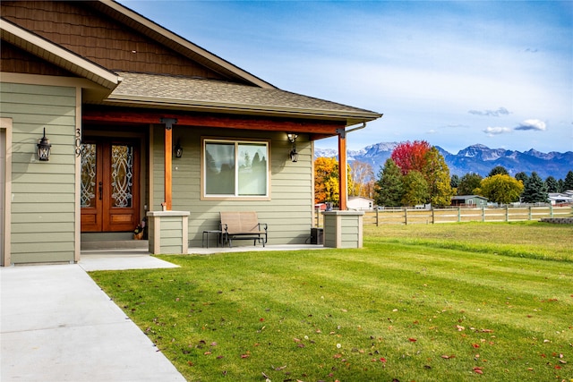 doorway to property with a mountain view and a yard