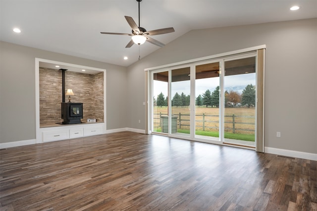 unfurnished living room featuring a wood stove, ceiling fan, dark wood-type flooring, and lofted ceiling