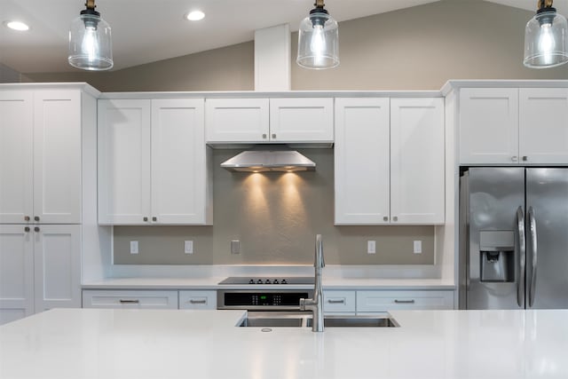 kitchen with stainless steel fridge, white cabinets, and vaulted ceiling