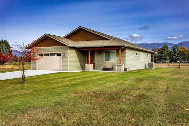 view of front of home featuring a mountain view, a front lawn, a garage, and central AC unit