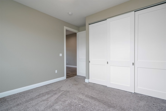 unfurnished bedroom with light colored carpet and a closet