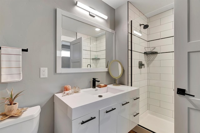 bathroom with a tile shower, vanity, and toilet