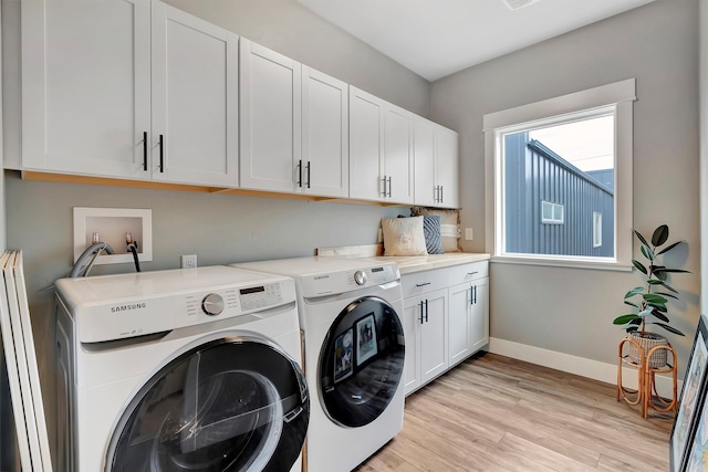 washroom with washer and dryer, cabinets, and light wood-type flooring