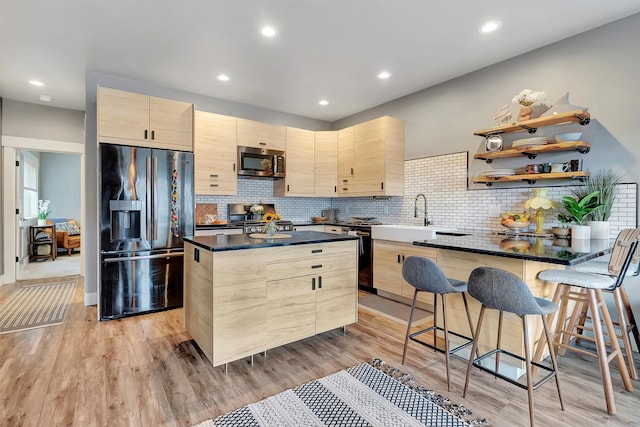 kitchen featuring light brown cabinetry, a kitchen island, light hardwood / wood-style floors, and appliances with stainless steel finishes