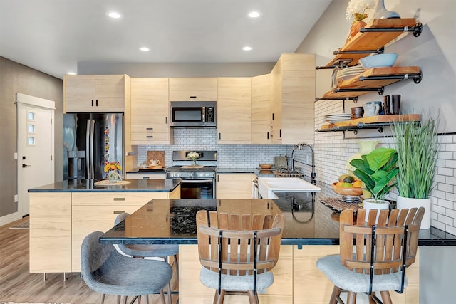 kitchen featuring sink, a center island, stainless steel appliances, light brown cabinets, and light wood-type flooring