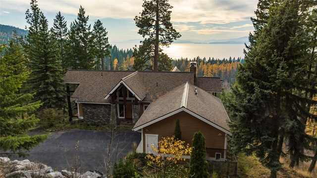 32054 Birch Tree Dr, Bigfork, MT 59911 - view of front facade with roof with shingles, a chimney, and a wooded view