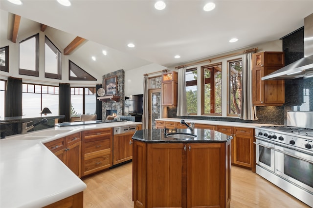 kitchen with a center island with sink, range with two ovens, a healthy amount of sunlight, and light hardwood / wood-style flooring