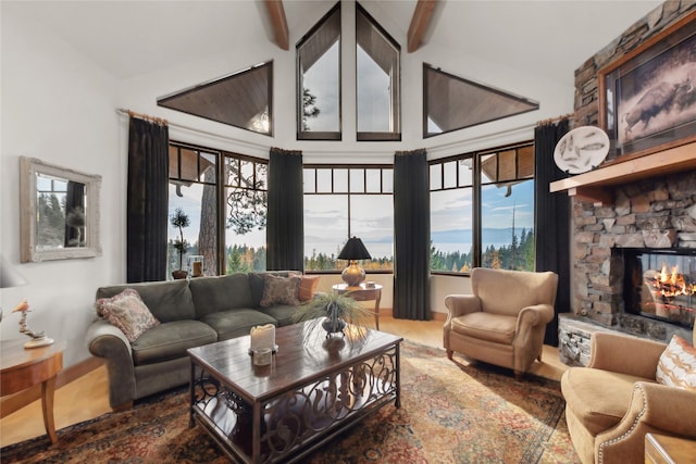 living room featuring beam ceiling, a stone fireplace, hardwood / wood-style floors, and high vaulted ceiling