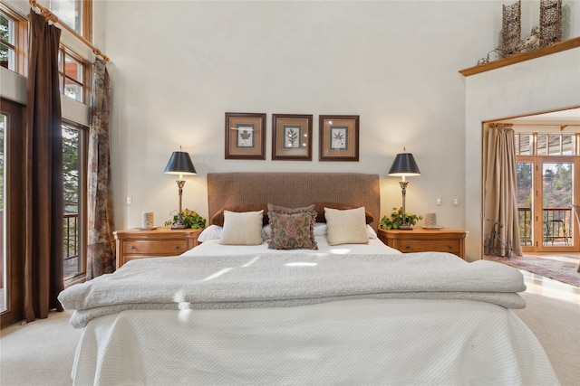 carpeted bedroom featuring access to exterior and a high ceiling