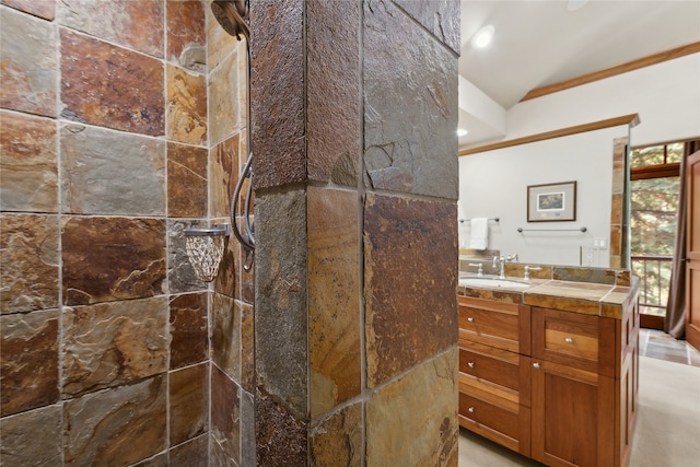 bathroom featuring vanity, tiled shower, crown molding, and vaulted ceiling