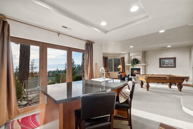 32054 Birch Tree Dr, Bigfork, MT 59911 - kitchen featuring a breakfast bar, dark countertops, light colored carpet, recessed lighting, and a raised ceiling