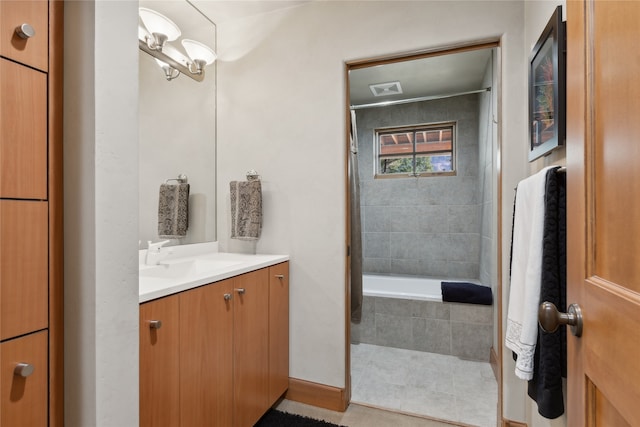 bathroom with tile patterned flooring, vanity, and tiled tub