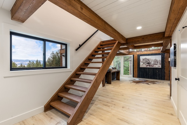 stairway with beam ceiling, hardwood / wood-style flooring, and plenty of natural light