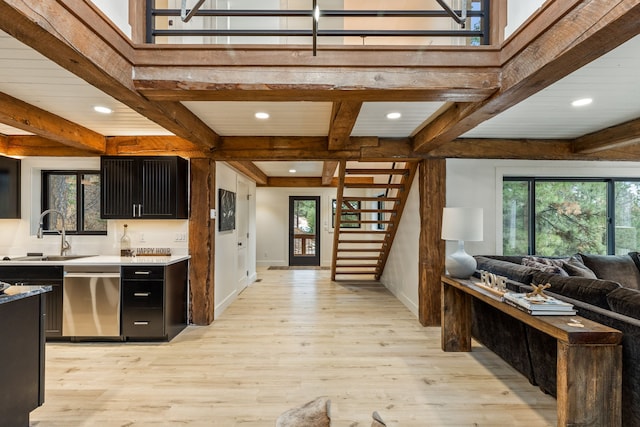 kitchen featuring sink, dishwasher, beamed ceiling, and light wood-type flooring