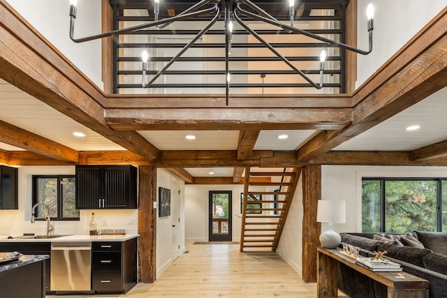 kitchen featuring stainless steel dishwasher, plenty of natural light, beam ceiling, and light hardwood / wood-style flooring