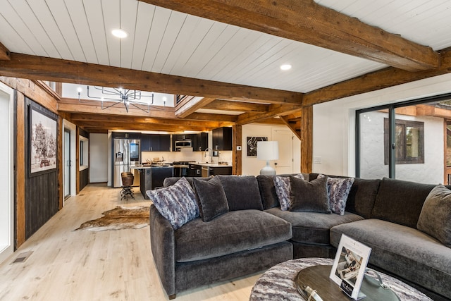 living room with light hardwood / wood-style flooring, beamed ceiling, wood ceiling, and sink