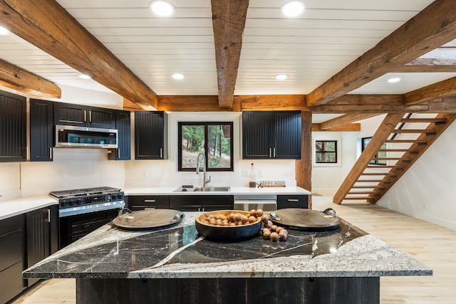 kitchen featuring beam ceiling, light stone countertops, sink, a center island, and appliances with stainless steel finishes