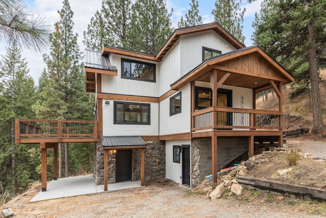 469 Owings Creek Loop, Hamilton, MT 59840 - view of front facade featuring stone siding, a metal roof, a patio, and a standing seam roof
