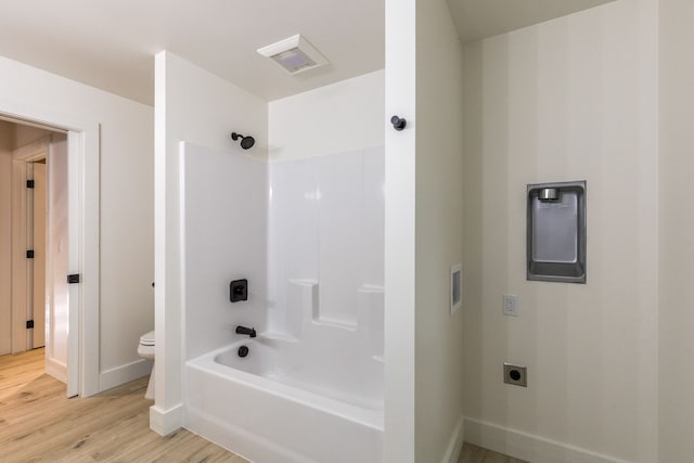 bathroom featuring hardwood / wood-style flooring, toilet, and tub / shower combination