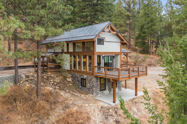 469 Owings Creek Loop, Hamilton, MT 59840 - back of house featuring stone siding, a patio area, a wooden deck, and a metal roof