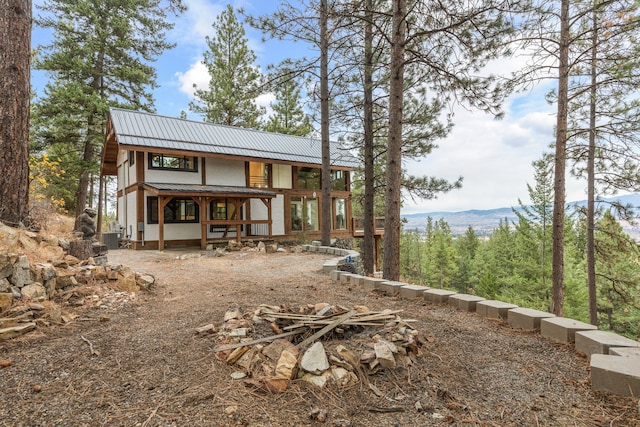 back of property with a mountain view, a fire pit, and cooling unit