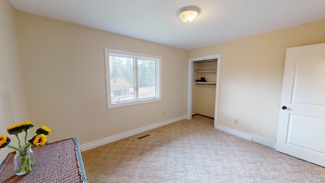 unfurnished bedroom featuring light carpet and a closet