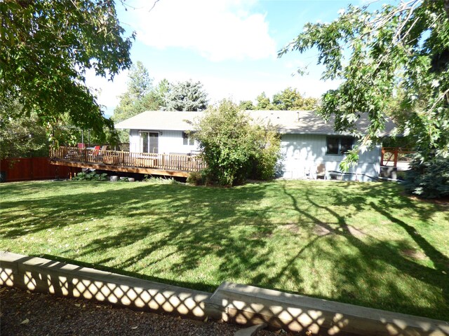 rear view of property featuring a yard and a deck