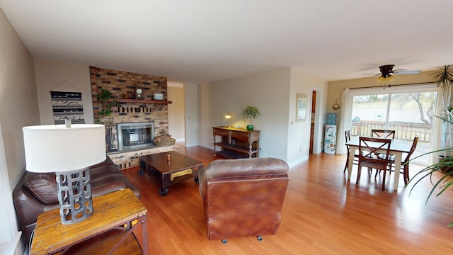 living room with ceiling fan, light hardwood / wood-style floors, and a brick fireplace