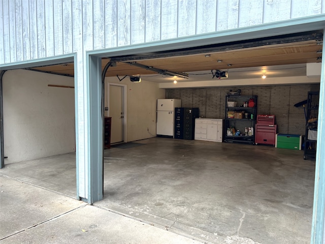 garage featuring white fridge and a garage door opener