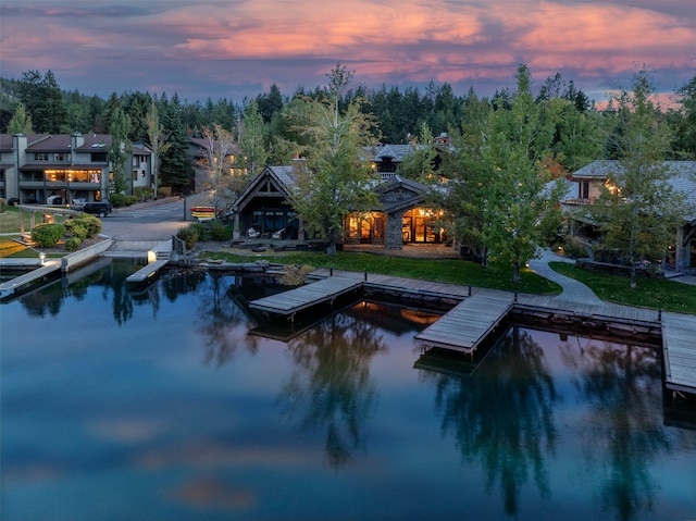 pool at dusk with a boat dock and a water view